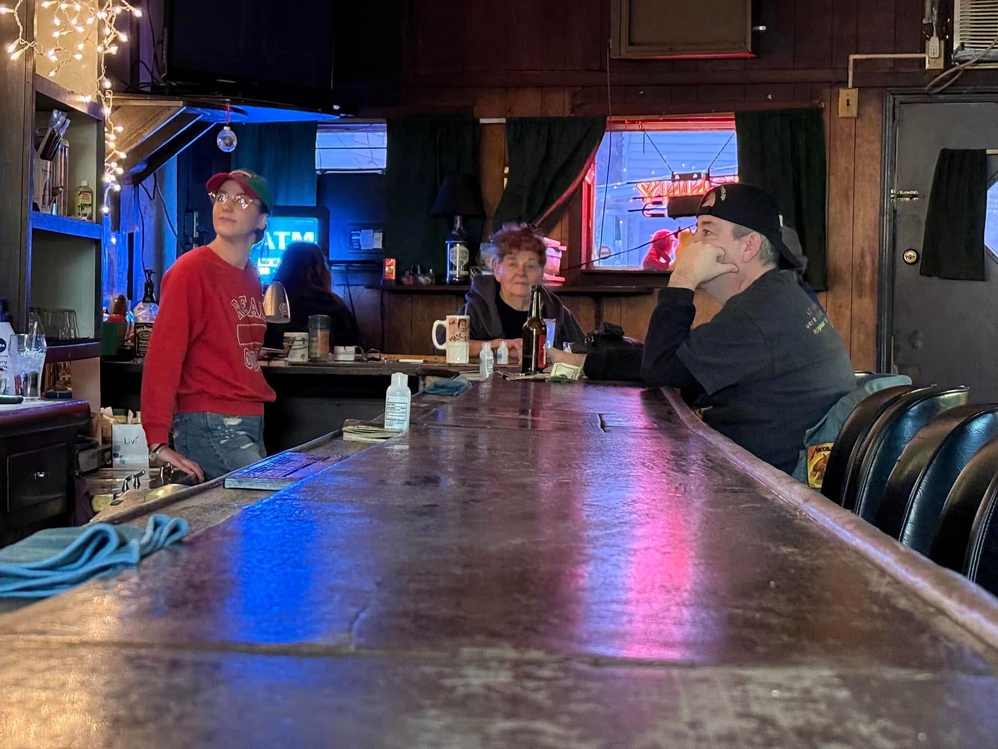 Sherry and another person sitting at the bar with a bartender behind the bar.