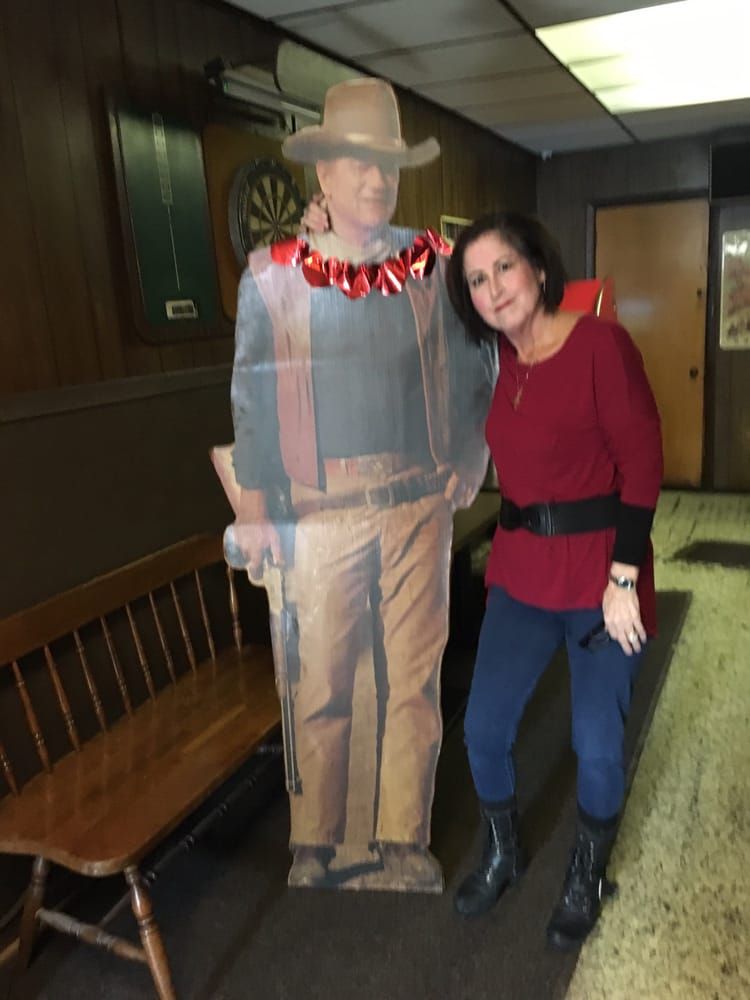 Woman with her arm around a life-size cutout of John Wayne