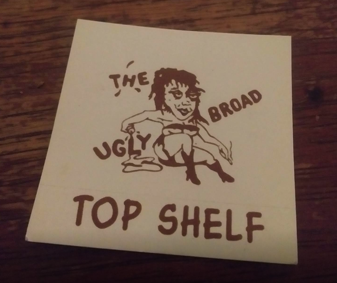 Card with The Ugly Broad logo that says 'Top Shelf'.