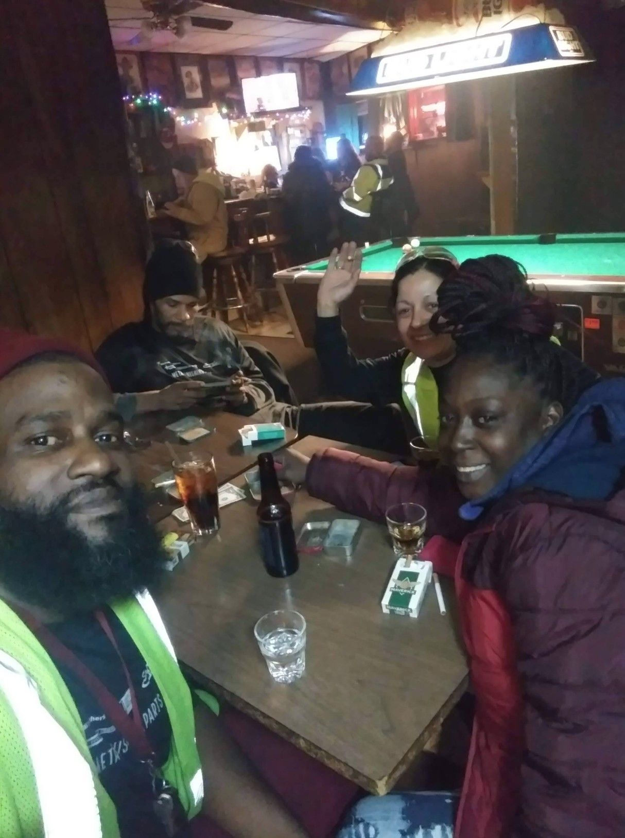 People drinking and smoking at a table inside The Ugly Broad.