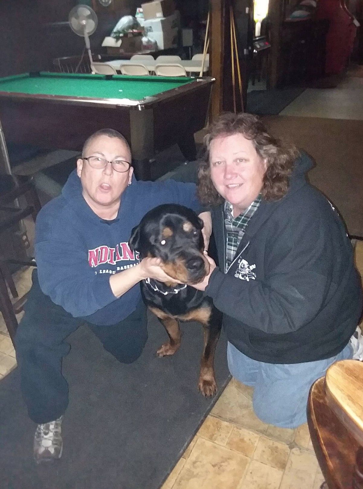 Two people with their arms around a dog.