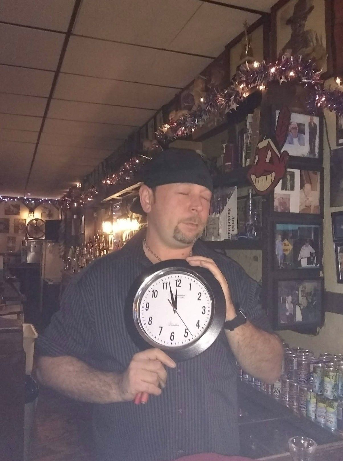 Man behind bar holding a clock.