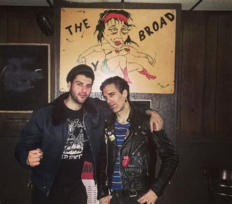 Two men standing in front of The Ugly Broad sign inside the bar.