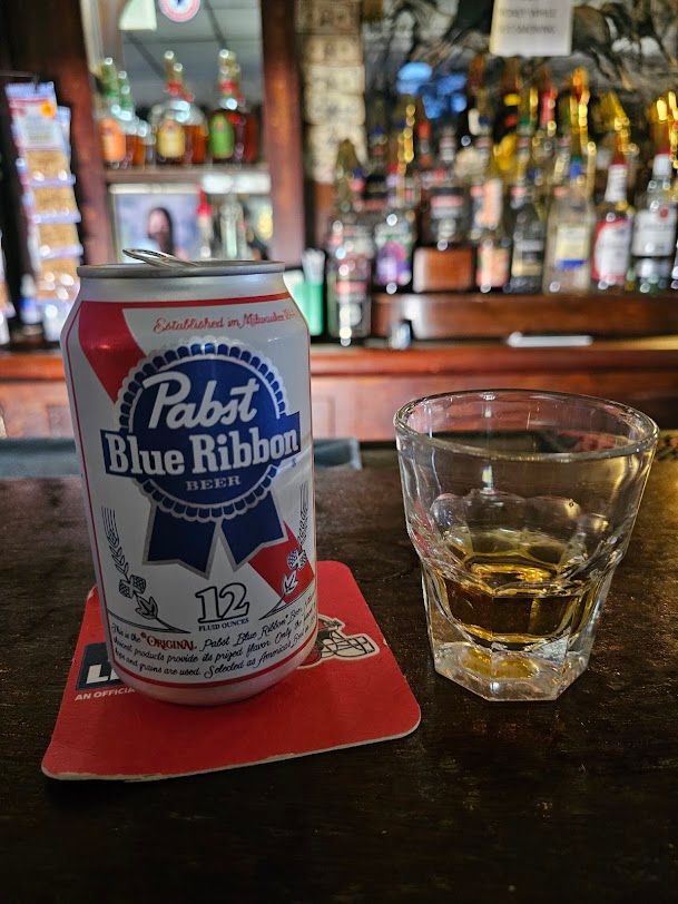 Close-up of a shot glass and a can of Pabst Blue Ribbon.