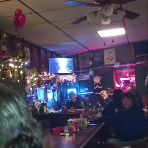 People sitting around the bar with Christmas decorations around.