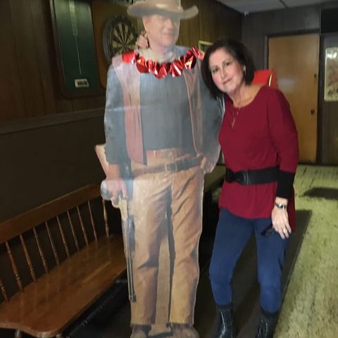 Woman with her arm around a life-size cutout of John Wayne