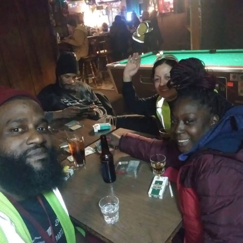 People drinking and smoking at a table inside The Ugly Broad.