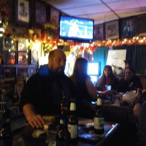 People at the bar with bartenders behind the bar.
