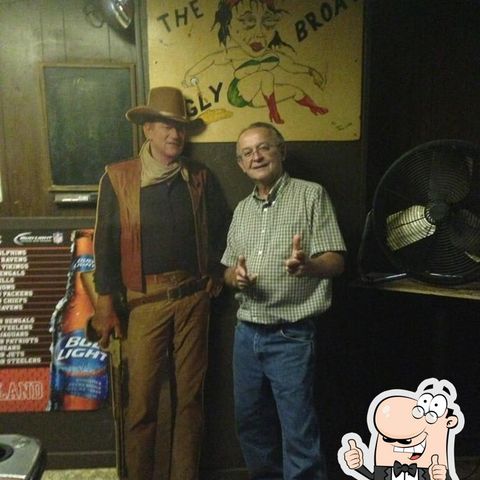 Man standing with cardboard cut-out of John Wayne.