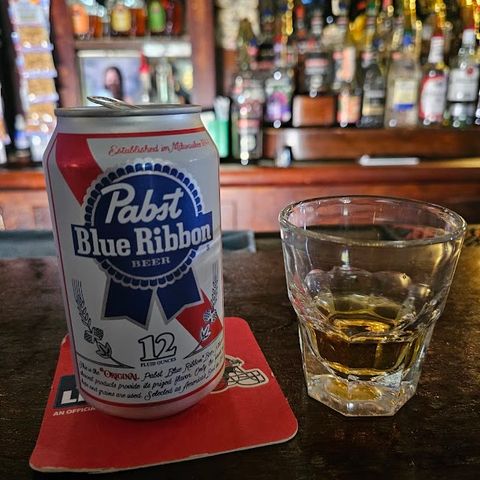 Close-up of a shot glass and a can of Pabst Blue Ribbon.